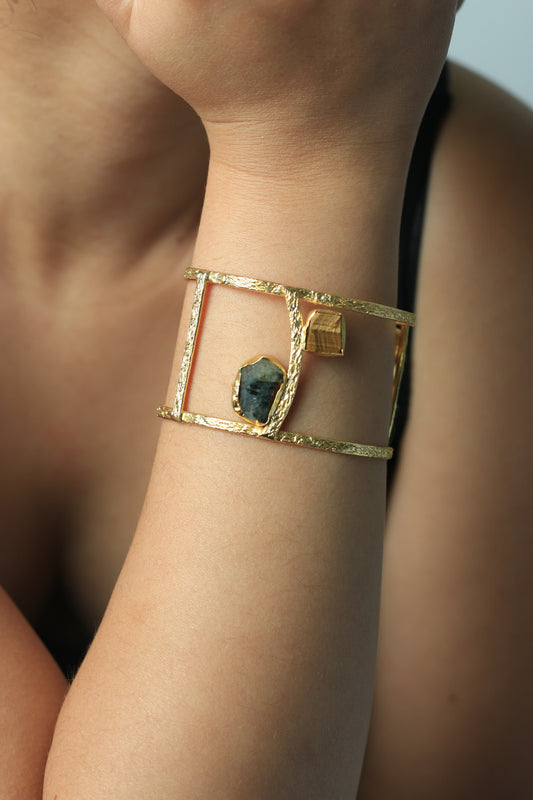 Gold bracelet with a central gemstone on a wrist